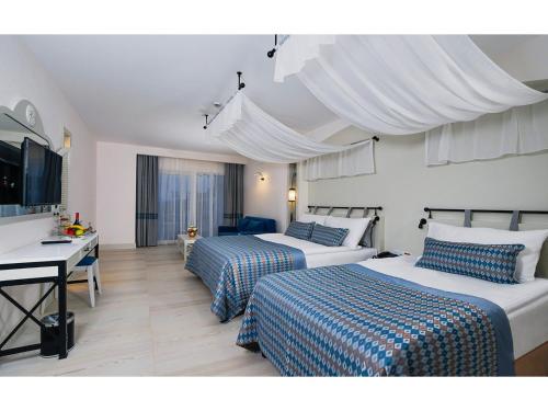 a hotel room with two beds and a desk at Limak Cyprus Deluxe Hotel in Iskele