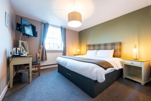 a bedroom with a bed and a desk and a television at Staunton Arms in Staunton in the Vale