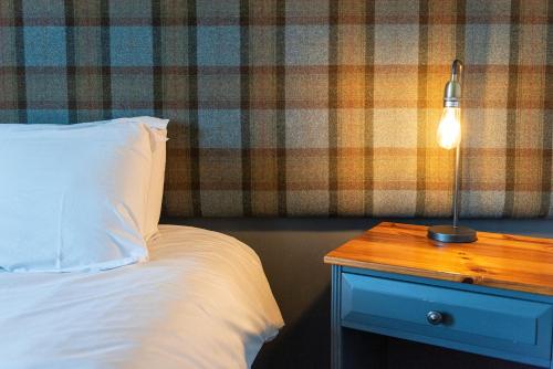 a bed with a white pillow and a lamp on a table at Staunton Arms in Staunton in the Vale
