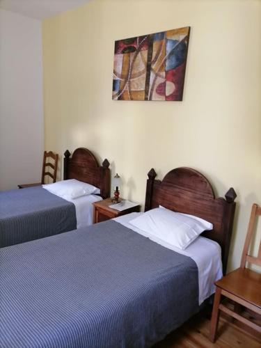 a bedroom with two beds and a painting on the wall at PENSÃO AVENIDA in Penacova