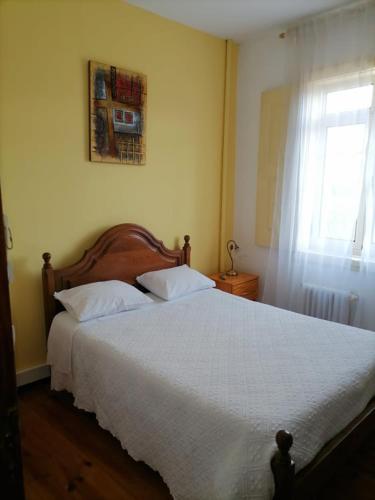 um quarto com uma cama grande com lençóis brancos e uma janela em PENSÃO AVENIDA em Penacova