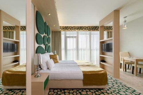 ハイドゥソボスローにあるHotel Aurum Family "A"のベッドとダイニングルームが備わるホテルルームです。