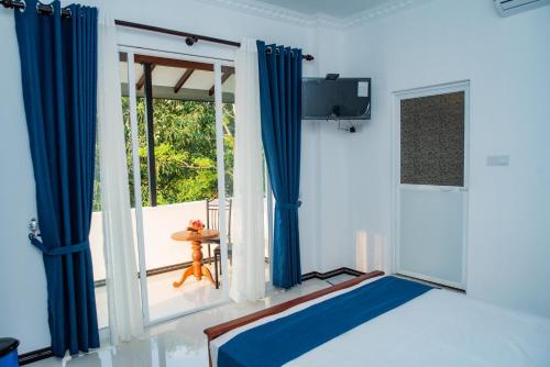 a room with blue curtains and a large window at Sky Edge Homestay in Kandy