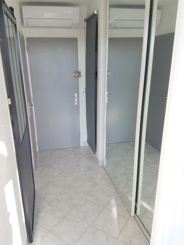 - un couloir avec des portes en verre et du carrelage dans l'établissement Studio Village Naturiste Caprice, au Cap d'Agde