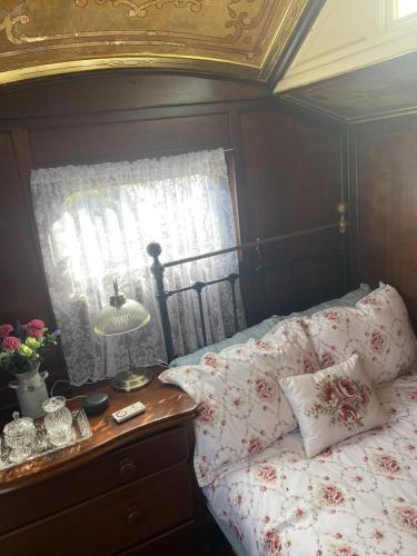 a bedroom with a bed with a table and a window at Vintage Showman's Wagon For Two Close to Beach in Plymouth