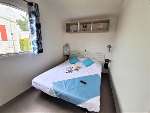 Cette petite chambre comprend un lit avec des oreillers bleus. dans l'établissement Camping la Prairie, à Saint-Hilaire-de-Riez