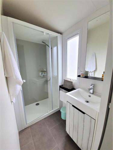 une salle de bain blanche avec une douche et un lavabo dans l'établissement Camping la Prairie, à Saint-Hilaire-de-Riez
