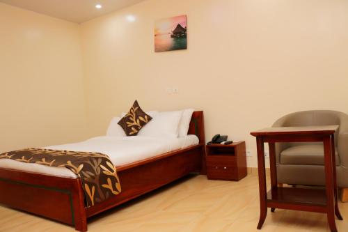 a bedroom with a bed and a chair in it at HOTEL LAVAL in Abidjan