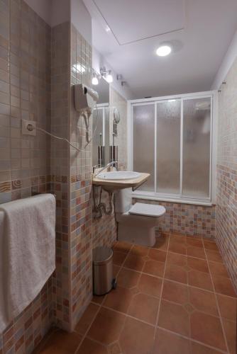 a bathroom with a toilet and a sink and a shower at Hostal EL GRIEL NO DISPONEMOS DE RECEPCIÓN FÍSICA in Hervás