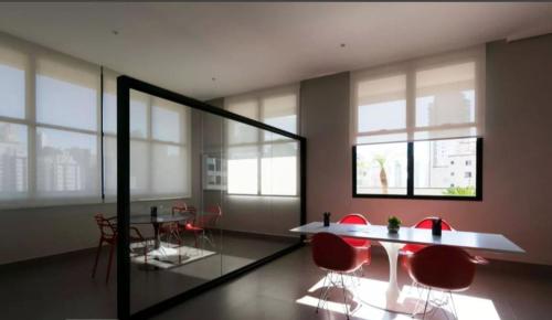 Cette chambre comprend des chaises rouges, une table et des fenêtres. dans l'établissement VN CASA TOPÁZIO - VILA MARIANA, à São Paulo