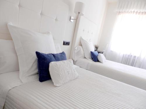 two white beds with blue pillows in a room at Hostal Carlos V in Puebla de Sanabria