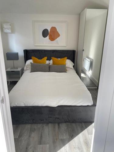 a bedroom with a large white bed with yellow pillows at Carriage Lodge - Stunning Apartment with parking in Wateringbury