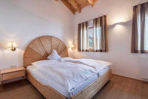 um quarto com uma cama grande e uma cabeceira em madeira em Ferienparadies Sabina Birke em Alpe di Siusi