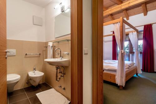 a bathroom with a sink and a toilet and a bed at Ferienparadies Sabina Lärche in Alpe di Siusi