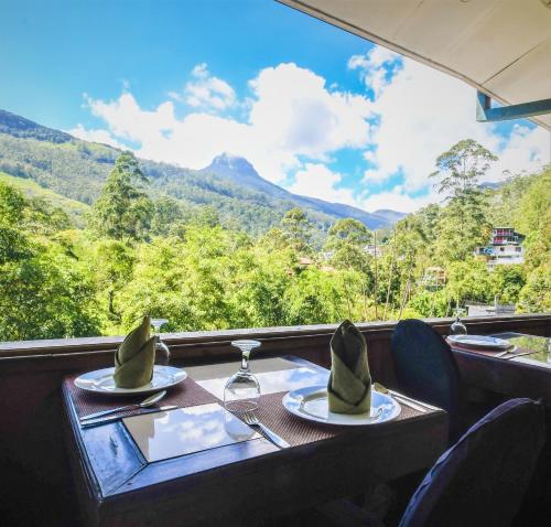 a table with two plates of food and a view of mountains at Wathsala Inn in Adams Peak