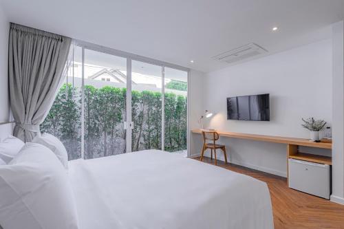 a white bedroom with a bed and a window at Casa 33 Hatyai in Hat Yai