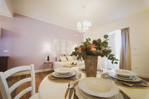 a dining room table with plates and a vase with flowers at ALMASOL - Charme Experience in Castellana Grotte