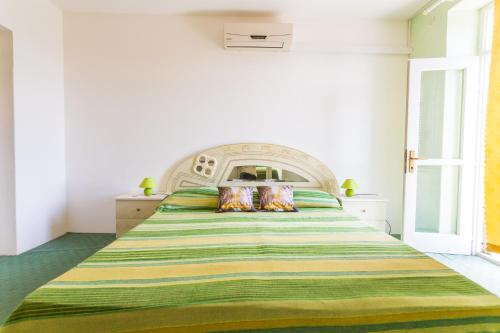 - une chambre avec un grand lit et une couverture verte et jaune dans l'établissement Apartments Sany, à Cavtat