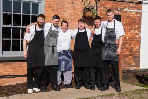 a group of men wearing aprons standing in front of a brick building at Staunton Arms in Staunton in the Vale