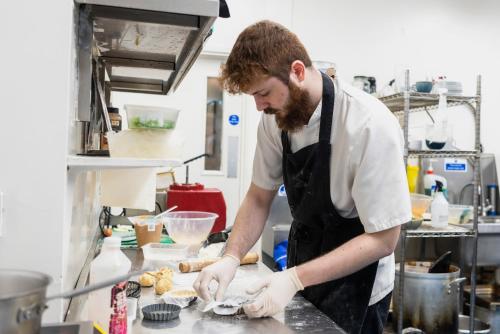 a man in a kitchen preparing food at Staunton Arms in Staunton in the Vale