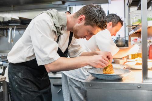 two men in a kitchen preparing food in a bowl at Staunton Arms in Staunton in the Vale