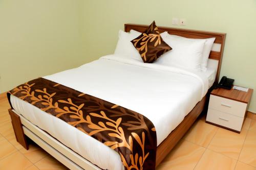 a bedroom with a large bed with a brown and white blanket at HOTEL LAVAL in Abidjan