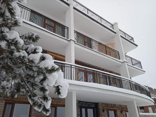 a white building with snow on the balconies at Mood Hotel Kazbegi in Stepantsminda