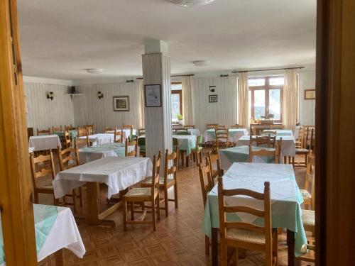 una sala da pranzo con tavoli e sedie con tovaglie bianche di Hotel Beau Sejour a Champorcher