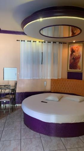 a bedroom with a large bed and a table at Versat Motel in Barretos