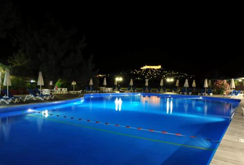 a large blue swimming pool at night at Delfinia Hotel & Bungalows in Mithymna