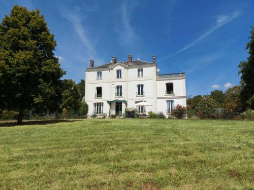 ein großes weißes Haus auf einem Grasfeld in der Unterkunft Manoir Le Parc near Paris & Disneyland in Villevaudé