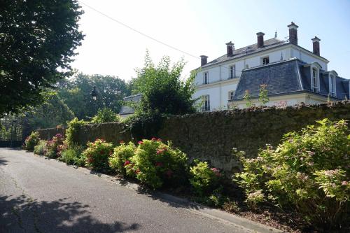 una gran casa blanca con una valla y flores en Manoir Le Parc near Paris & Disneyland, en Villevaudé