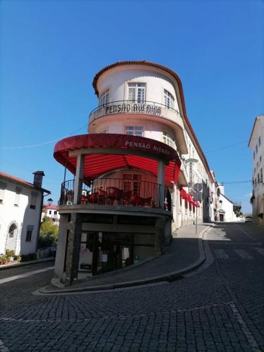 un edificio su una strada con un edificio con balcone di PENSÃO AVENIDA a Penacova