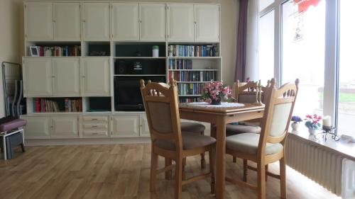 een keuken met een tafel en stoelen en een boekenplank bij Haus Baltic App 132 - gleich hinter dem Deich, sonnige Balkonwohnung in Südwestlage in Grömitz
