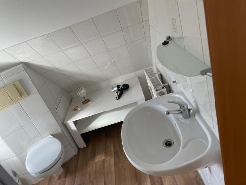 uma casa de banho branca com um lavatório e um WC em Fewo 5 em Elmenhorst