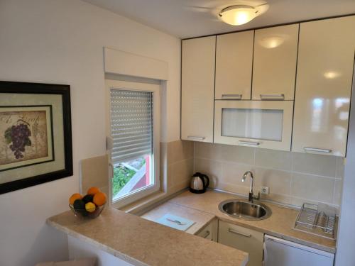 a kitchen with white cabinets and a sink and a window at Apartment Rachel in Petrovac na Moru