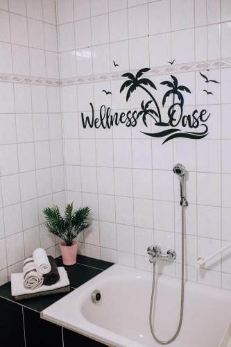 a bathroom with a white tiled wall with a welcome loss sign at An der Kastanie in Wiesmoor
