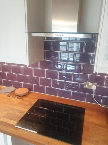 a kitchen with purple tiles on the wall at Amazing 2 Bed 2 Bath Apartment City Centre Free Secure Parking in Cardiff