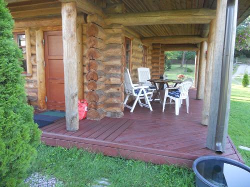a porch of a log cabin with a table and chairs at Forest Edge Lodge in Rīga