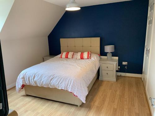 a bedroom with a bed and a blue wall at Entire Family Entertainment Holiday Home - 3 x Floors - Free Parking - Games Room - Private Garden - Workspace and Wifi 112mb - Self Check-in in Ashford