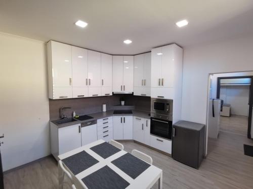 een keuken met witte kasten en een zwarte koelkast bij AApartman Exclusive in Pécs