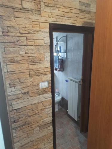 a bathroom with a stone wall next to a toilet at Appartamento Savona in Savona