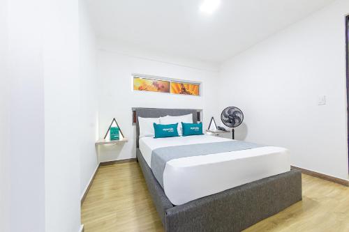 1 dormitorio blanco con 1 cama grande con almohadas azules en Ayenda Bee Hotel, en Pereira