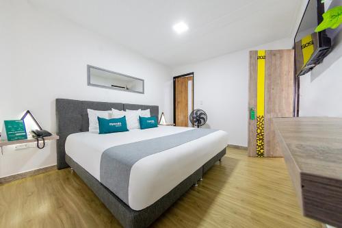 1 dormitorio con 1 cama grande con almohadas azules en Ayenda Bee Hotel, en Pereira