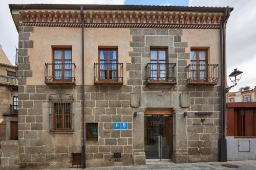 ein altes Steingebäude mit Fenstern und Balkonen in der Unterkunft María Pacheco Hotel Boutique in Avila