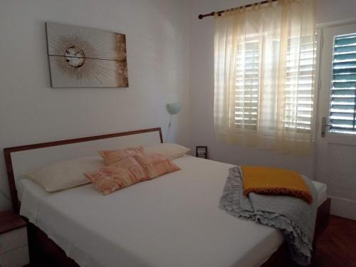 a bedroom with a bed with white sheets and a window at Holiday Home Dragan - 50m from sea in Splitska