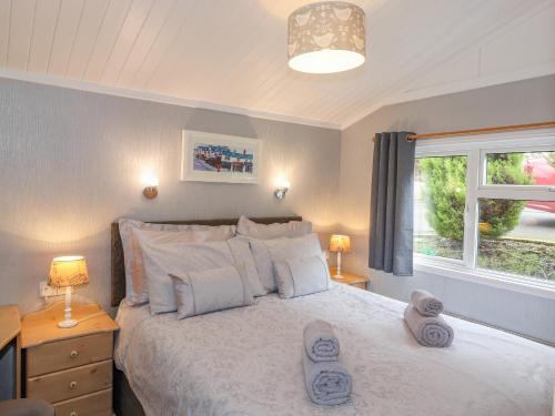 a bedroom with a white bed with two lamps and a window at Limefitt Lodge in Windermere