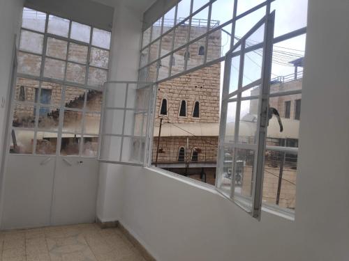 an empty room with a large window and a building at Dar Jacaman - In the heart of Bethlehem old city in Bethlehem