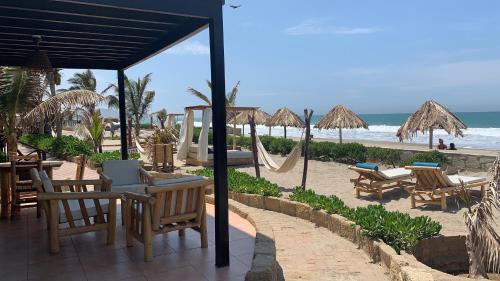 a beach with chairs and umbrellas and the ocean at El Refugio de Vichayito in Vichayito