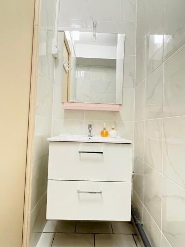 une salle de bain blanche avec un lavabo et un miroir dans l'établissement 702 Studio cosy à proximité de Paris 20ème, à Bagnolet